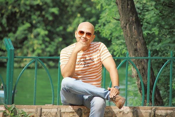 uomo contento che prende il sole in un parco ma che soffre di calvizie