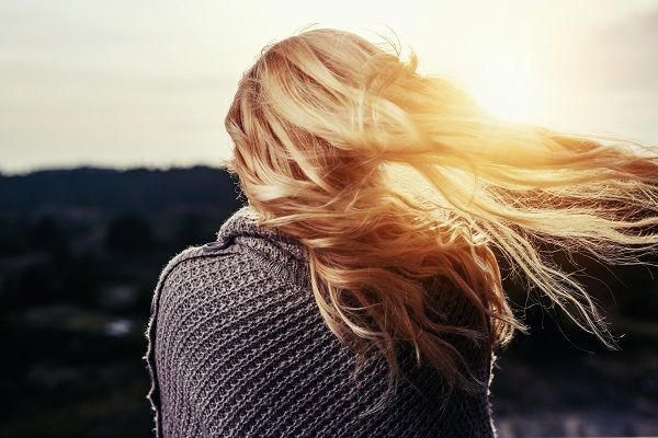 donna girata di spalle, con lunghi capelli biondi e lisci