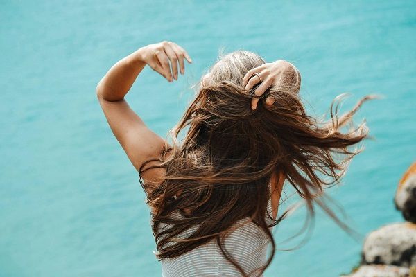 donna girata di spalle e con lunghi capelli castani e crespi