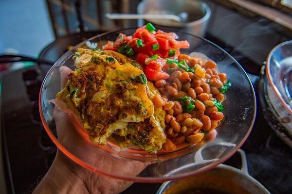 persona che ha un piatto con fagioli ed una frittata