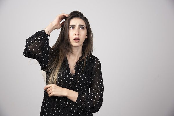 Ritratto di ragazza pensierosa che tiene le mani sulla testa.