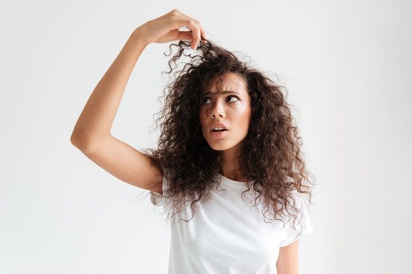 donna che guarda i suoi capelli ricci perché ha i capelli fragili