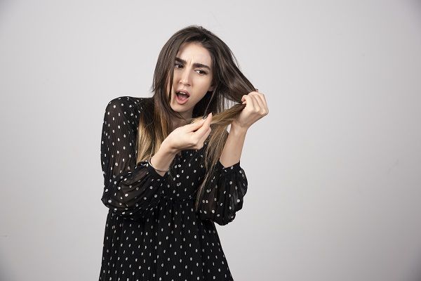 Una bella donna giovane che tiene in mano i suoi capelli sani e lucenti.