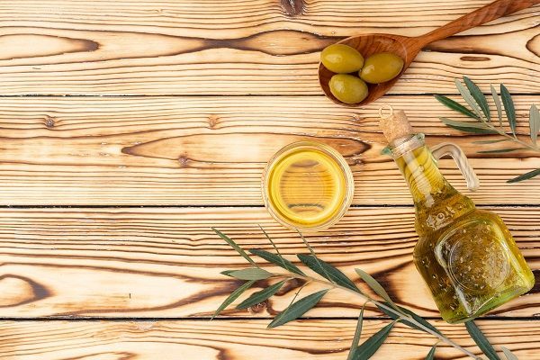 Olive e bottiglia di olio d'oliva su sfondo in legno, primo piano