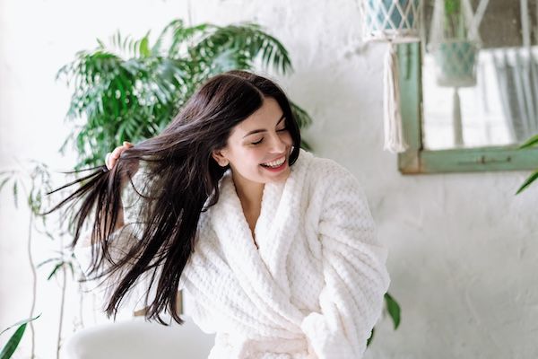 donna in bagno si appresta a lavare i capelli pianta nello sfondo