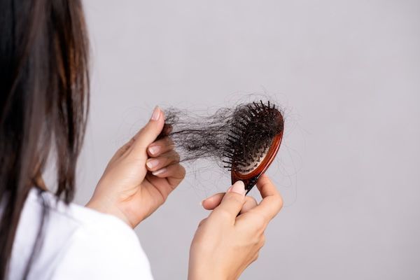 La donna mostra la sua spazzola con i capelli danneggiati e caduti."