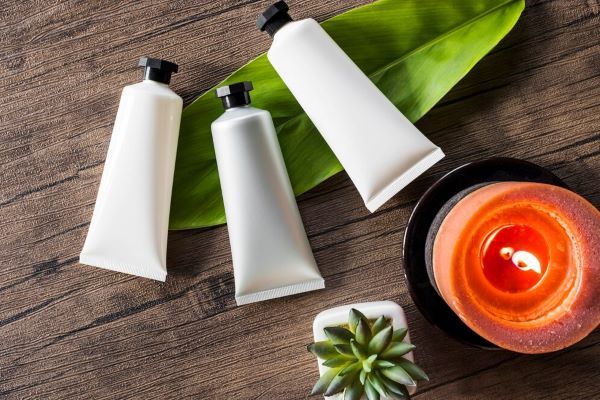 Tre prodotti cosmetici spa con candela accesa su sfondo in legno