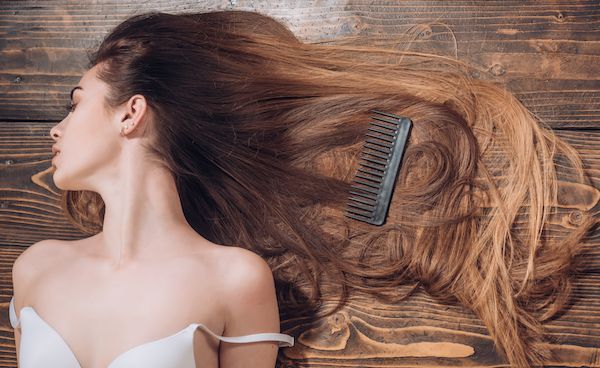 donna con capelli bellissimi su una superficie di legno pettine