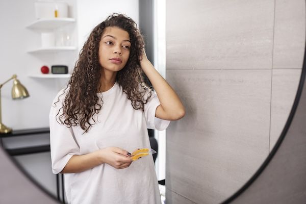 Donna a mezza figura capelli lunghi che si guarda allo specchio
