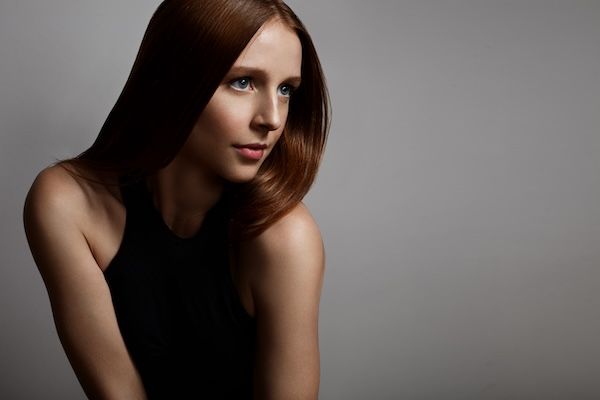 Ragazza dai capelli rossi con occhi azzurri su sfondo grigio capelli lucidi