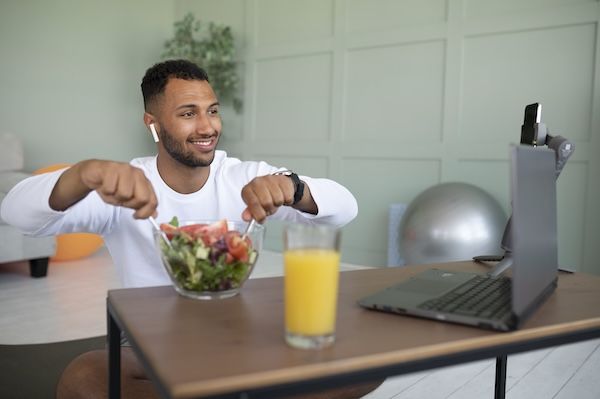 Uomo a mezzobusto che mescola un'insalata.