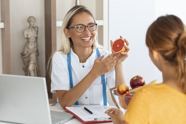 Nutrizionista donna che dà una consulenza al paziente, elaborando un piano dietetico nella clinica per la perdita di peso