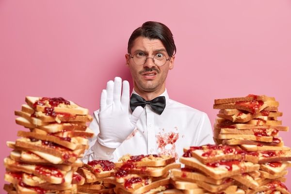 Giovane attraente circondato da sandwich di burro di arachidi e gelatina.