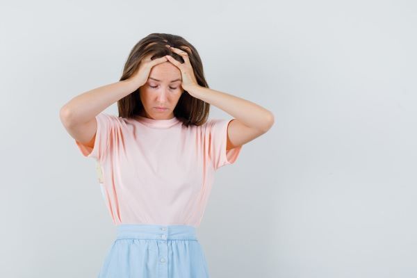 La ragazza si tiene la testa con le mani e fa un'espressione stanca.