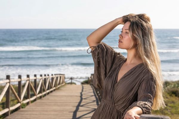 Ragazza dai capelli lunghi che prende il sole sulla spiaggia.