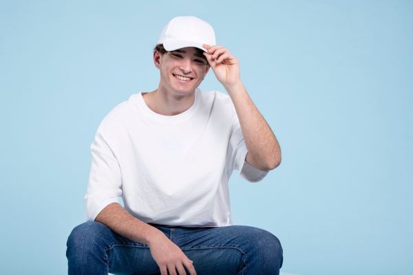 Uomo seduto sorridente con un berretto.