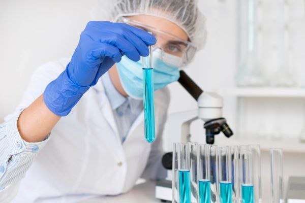 Donna che tiene un tubo con liquido in laboratorio.