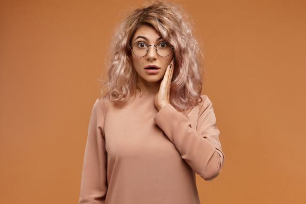 Ragazza con gli occhiali e capelli secchi e danneggiati. I capelli opachi sono spesso secchi e opachi.