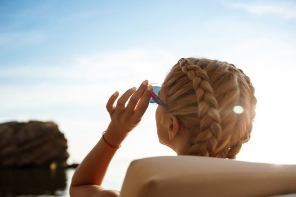 Ragazza bionda con gli occhiali e le trecce che prendono il sole.