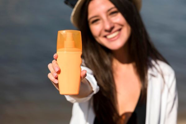 Ragazza sorridente che mostra protezione solare per capelli