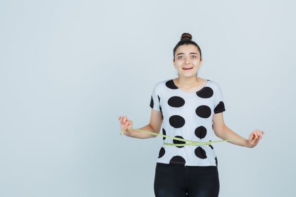 Ragazza in posa con un nastro di misurazione intorno alla vita