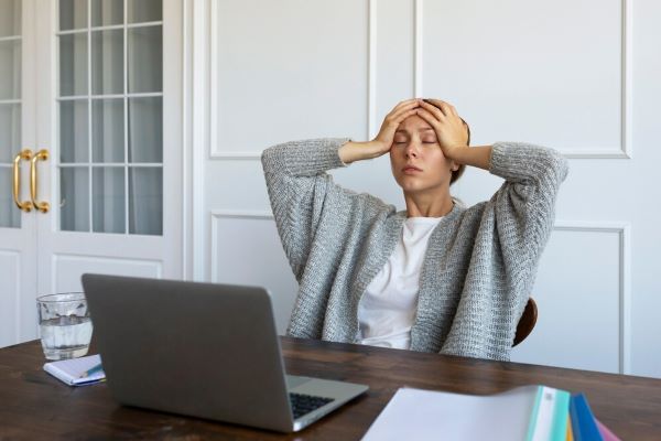 Ragazza seduta a un tavolo che fa gesti di preoccupazione e stress