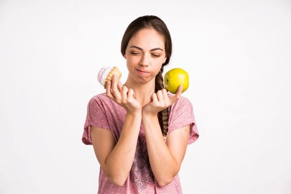 Ragazza indecisa tra una mela e un cupcake