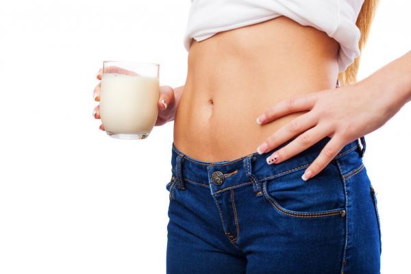 Ragazza in jeans e camicetta che beve un bicchiere di latte