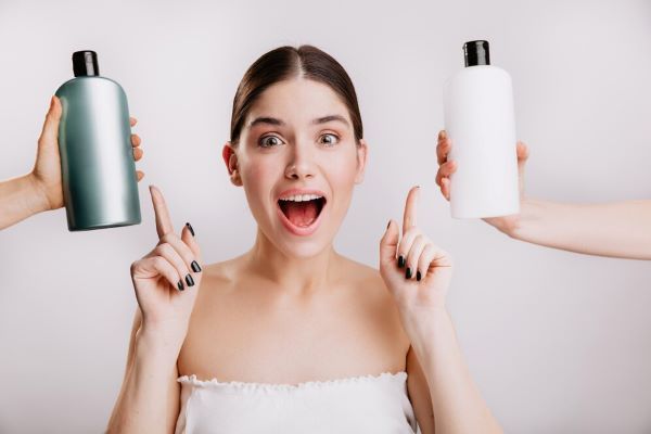 Ragazza felice che sceglie tra due diverse bottiglie di shampoo