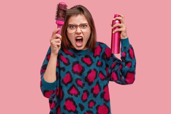 Ragazza con uno spray in una mano e un pennello nell'altra