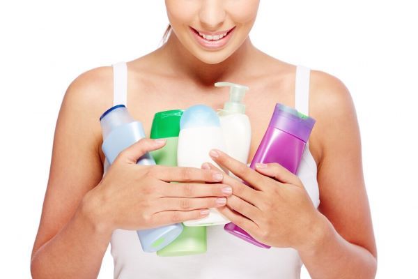 Ragazza con numerose bottiglie di prodotti per capelli