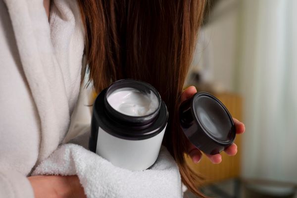 Donna che si applica la crema sui capelli