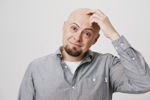 Uomo calvo che si gratta la testa