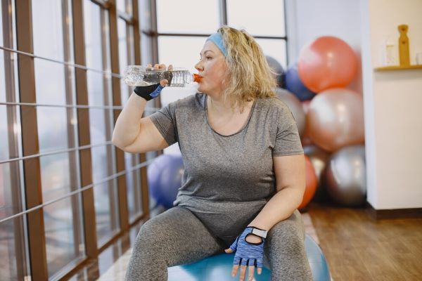 Signora seduta su un fitball e acqua potabile.