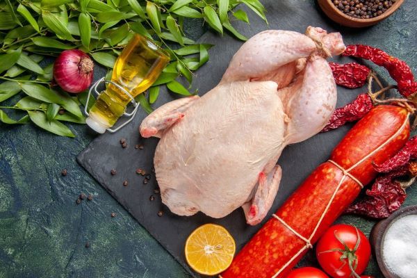 Pollo intero su una tavola di legno con verdure