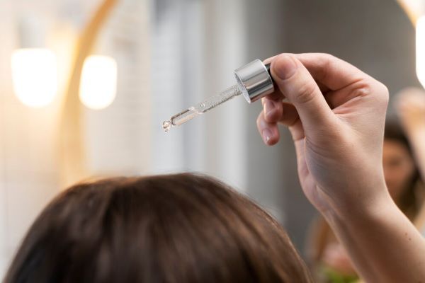 Ragazza che applica un siero sul cuoio capelluto