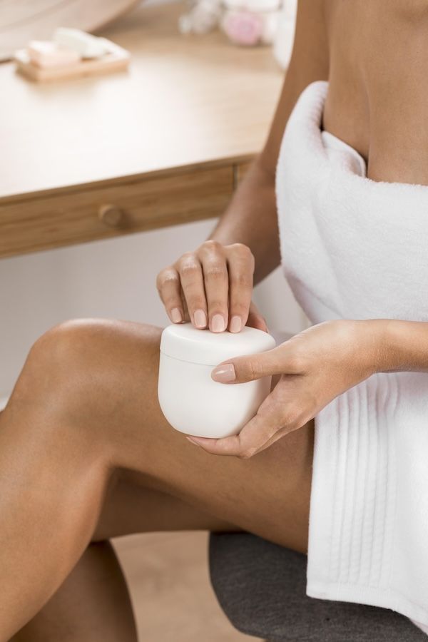 Bella giovane donna con crema struccante a casa