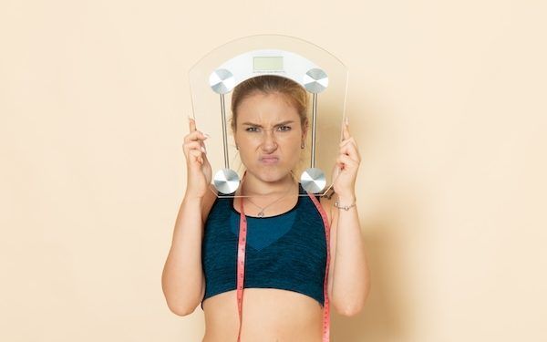 Vista frontale della giovane donna in tuta sportiva che tiene le scale sulla parete bianca in forma esercizi di salute del corpo di bellezza sportiva