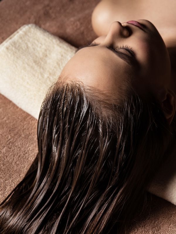 Giovane donna che riceve la procedura di cura dei capelli nel salone spa. Trattamento di bellezza. 