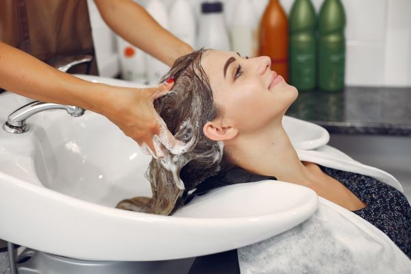 Donna che si lava la testa in un salone per capelli