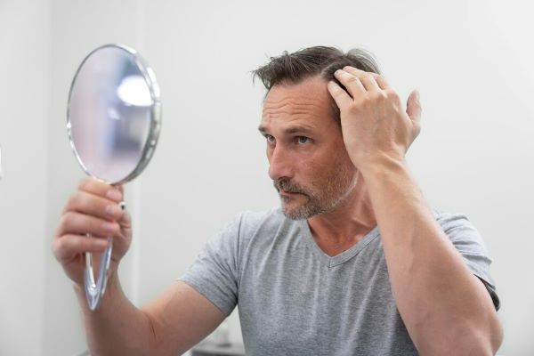 L'uomo preoccupato vede il suo riflesso nello specchio.