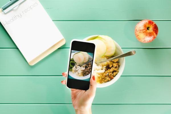 Ragazza che scatta foto del suo piatto. Molte app sono utili per tenere un diario alimentare.