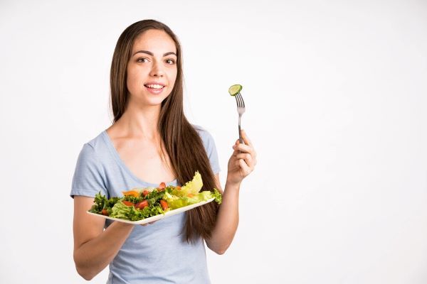 Ragazza che mangia un'insalata. Gli alimenti sani aiutano molto a dimagrire e a perdere peso.
