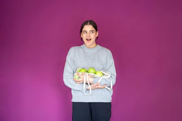 Ragazza felice che tiene alcuni frutti e un nastro di misurazione