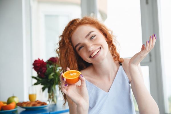 Ragazza sorridente con un'arancia in mano
