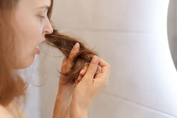 Ragazza sorpresa osservando le ciocche dei suoi capelli