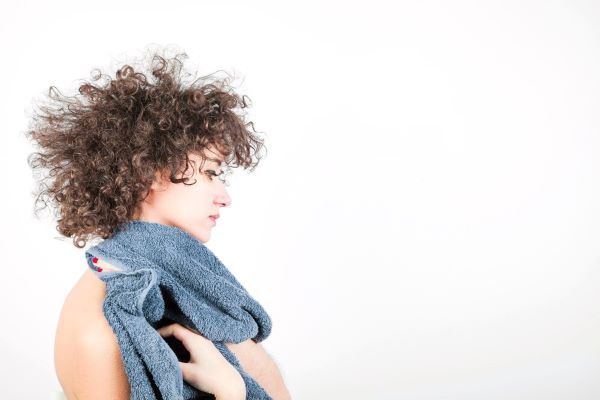 Giovane donna con capelli ricci che tiene un asciugamano