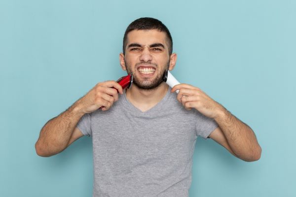uomo che sorride alla telecamera. Le carie nel sorriso potrebbero essere collegate alla calvizie.