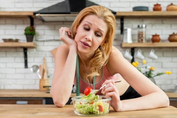Ragazza indecisa che guarda la sua insalata