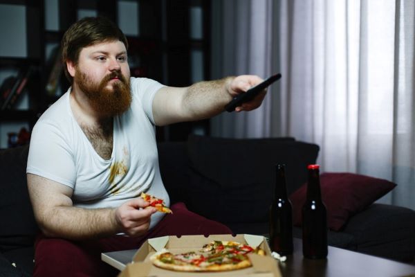 Ragazzo che guarda la TV mentre mangia la pizza